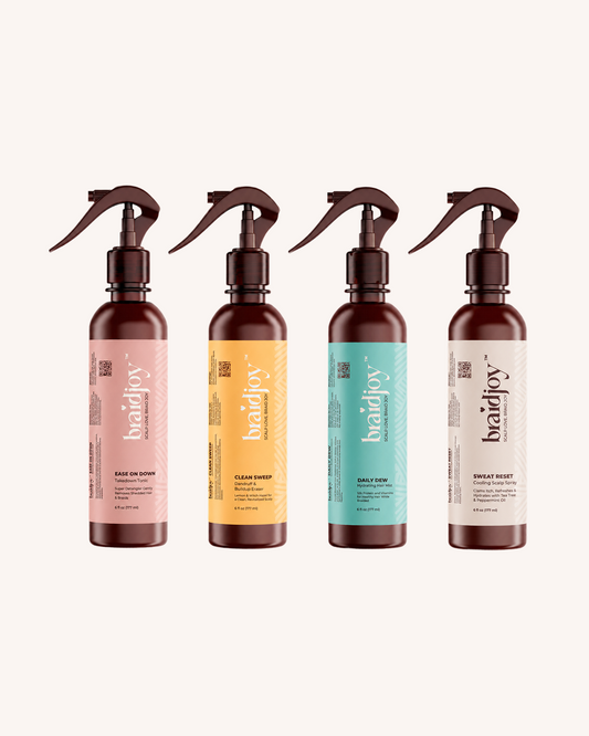 Full Braid Joy system with four amber spray bottles: Daily Dew hydration mist, Sweat Reset cooling scalp spray, Ease on Down detangler, and Clean Sweep scalp detox, designed to support healthier hair before, during, and after braids.