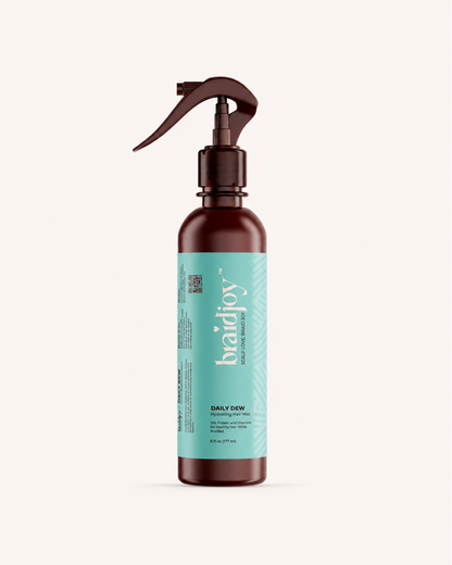 Amber braidjoy Daily Dew hydrating hair mist with a teal label on a light background, designed to keep braids moisturized, strengthen hair with aloe, silk protein, and vitamins, and support healthier hair after braids.