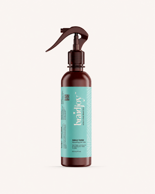 Amber braidjoy Daily Dew hydrating hair mist with a teal label on a light background, designed to keep braids moisturized, strengthen hair with aloe, silk protein, and vitamins, and support healthier hair after braids.